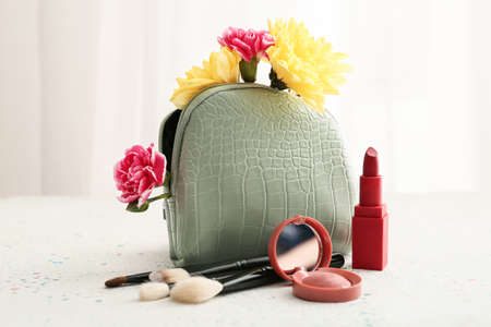 Stylish bag with decorative cosmetics and flowers on light backgroundの写真素材