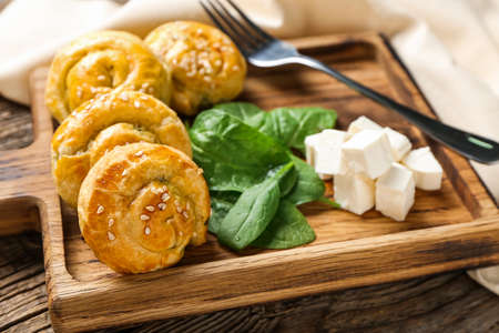 Puff pastry stuffed with spinach and feta cheese on wooden background