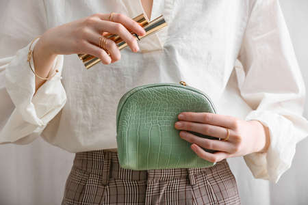 Woman with stylish bag and decorative cosmetics on light background, closeup