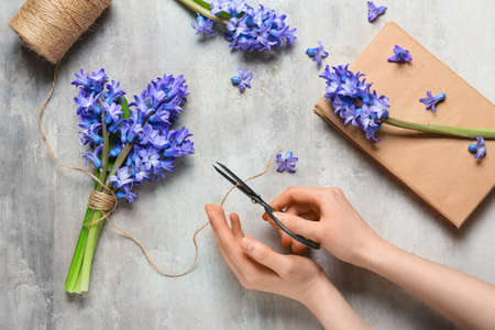 Woman making beautiful bouquet with hyacinth flowers on light background
