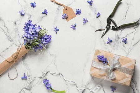 Composition with bouquet of beautiful hyacinth flowers, gift box and secateurs on light backgroundの写真素材