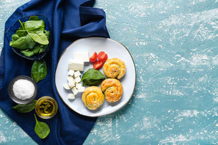 Puff pastry stuffed with spinach, feta cheese and tomatoes on color backgroundの写真素材