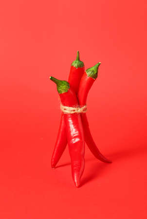 Bundle of hot chili peppers on red backgroundの写真素材