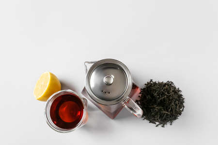 Composition of teapot and glass with tasty tea on light backgroundの写真素材