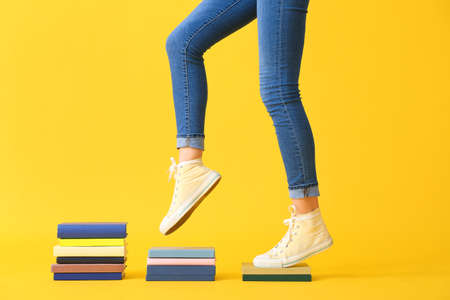 Creative composition with books and female legs on yellow backgroundの写真素材