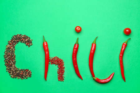 Word CHILI made of peppers, peppercorns and tomatoes on green backgroundの写真素材