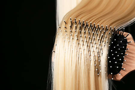 Brushing of long blond hair on dark backgroundの写真素材