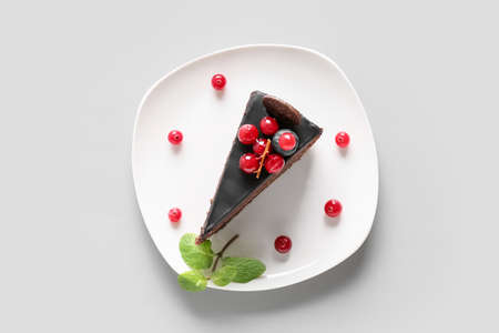Plate with delicious piece of chocolate cake and cranberries on light backgroundの写真素材