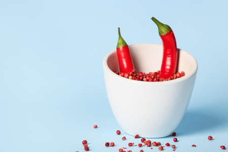 Bowl with chili peppers and red peppercorns on blue backgroundの写真素材