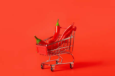 Shopping cart with hot chili peppers on red backgroundの写真素材