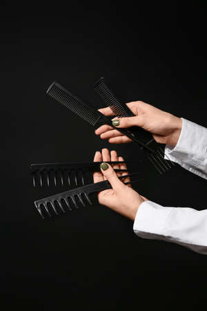 Female hands with hair combs on dark backgroundの写真素材