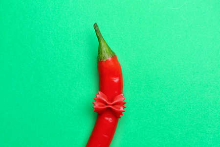 Hot chili pepper and pasta on green background