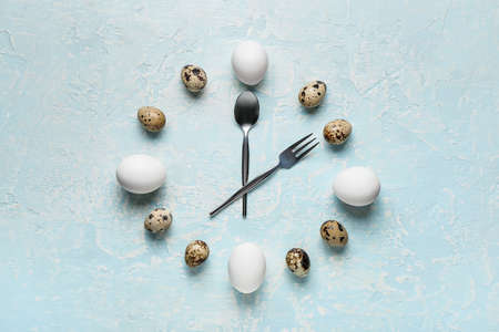 Clock made of eggs and cutlery on color backgroundの写真素材