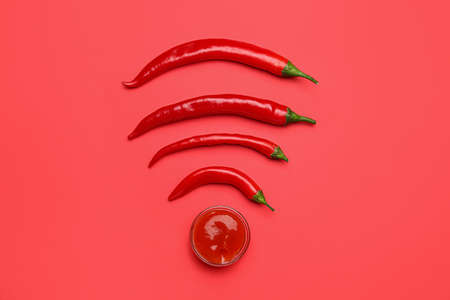 Hot chili peppers and bowl with sauce on red backgroundの写真素材