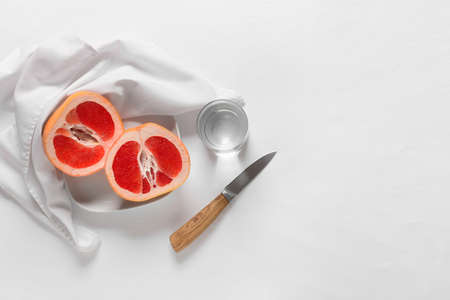 Plate with tasty grapefruit pieces and glass of water on light backgroundの写真素材