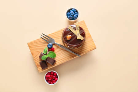 Board with delicious chocolate cake and berries on light backgroundの写真素材