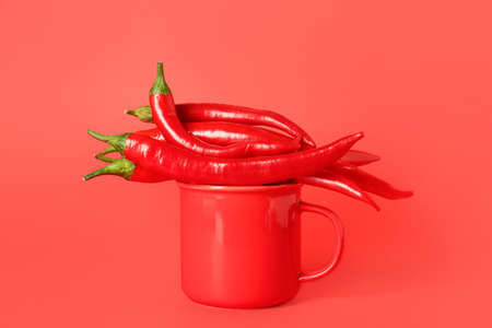 Mug with hot chili peppers on red backgroundの写真素材