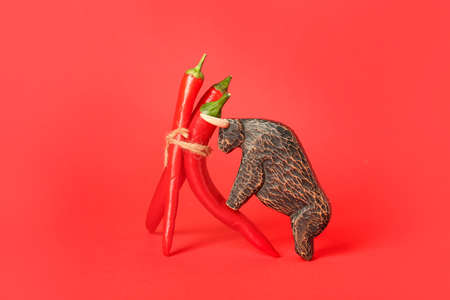 Hot chili peppers and wooden bull on red backgroundの写真素材