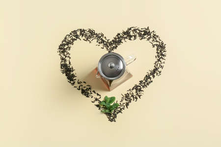 Heart shape made of tea and teapot on yellow backgroundの写真素材