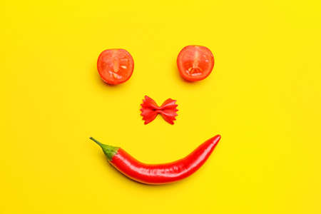 Smile made of hot chili pepper and tomatoes on yellow backgroundの写真素材