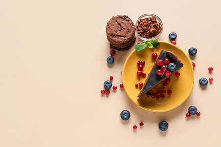 Plate with delicious piece of chocolate cake, cookies and berries on light background