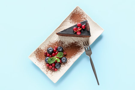 Plate with delicious piece of chocolate cake and berries on blue backgroundの写真素材