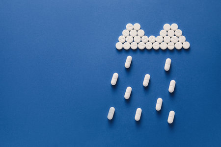 Rain cloud made of pills on blue backgroundの写真素材