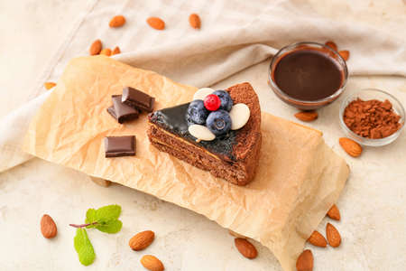 Board with delicious piece of chocolate cake and berries on light background