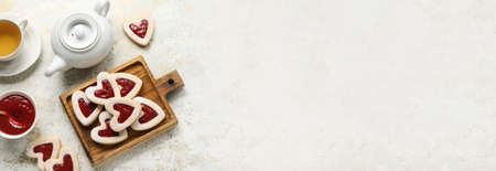 Board with tasty heart-shaped cookies and jam with tea on light background with space for text. Valentine's Day celebrationの写真素材