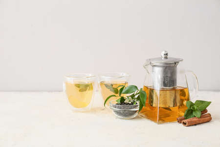 Teapot and glasses of tasty tea on light backgroundの写真素材