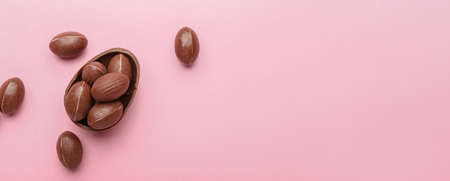Chocolate Easter eggs on pink background with space for textの写真素材