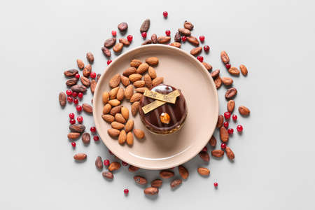 Plate with delicious chocolate cake, nuts and berries on light background