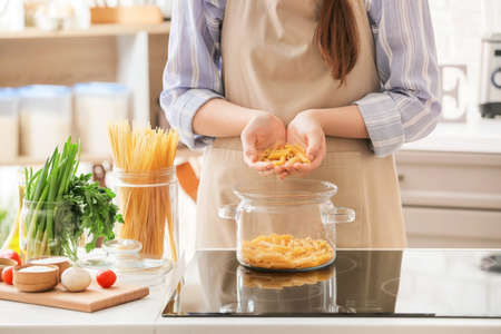 Young woman cooking tasty pasta in the kitchenの写真素材