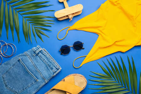 Composition with stylish sunglasses, clothes and palm leaves on blue backgroundの写真素材