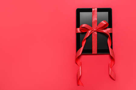 Tablet computer tied with ribbon on red backgroundの写真素材