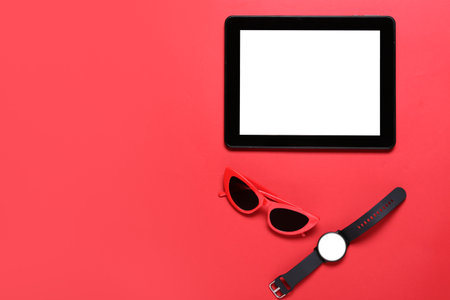 Tablet computer, smart watch and sunglasses on red backgroundの写真素材