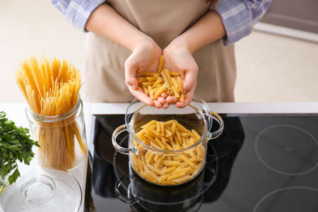 Young woman cooking tasty pasta in the kitchenの写真素材