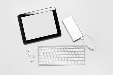Tablet computer, power bank, earphones and keyboard on white backgroundの写真素材