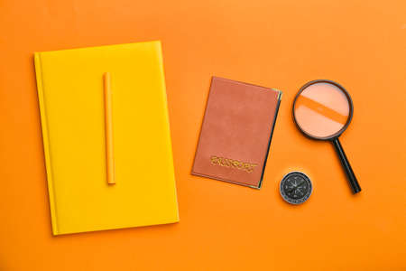 Notebook, passport, compass and magnifier on color backgroundの写真素材