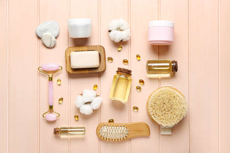 Composition with bottles of essential oil, pills and bath supplies on color wooden background