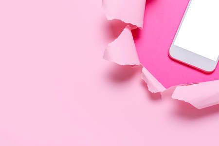 Mobile phone visible through torn color paper, closeupの写真素材