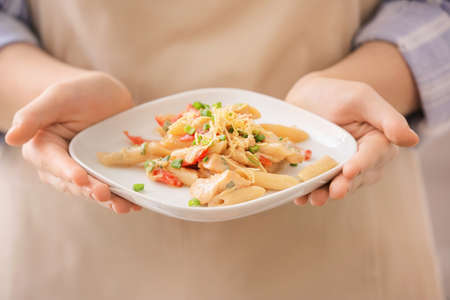 Woman with plate of cajun chicken pasta in kitchenの写真素材