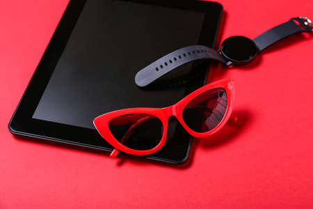 Tablet computer, smart watch and sunglasses on red background, closeupの写真素材