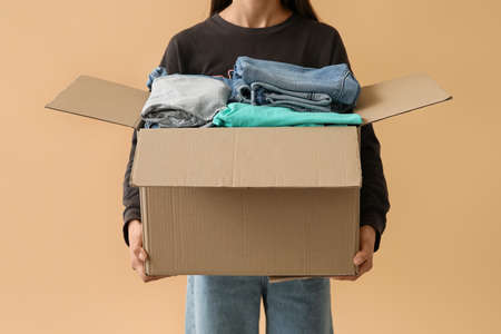 Woman and wardrobe box with clothes on color backgroundの写真素材