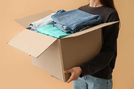 Woman and wardrobe box with clothes on color backgroundの写真素材