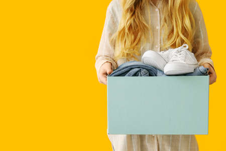 Woman and wardrobe box with clothes on color backgroundの写真素材