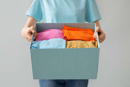 Woman and wardrobe box with clothes on light backgroundの写真素材