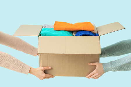 Women and wardrobe box with clothes on color background