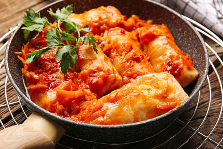 Frying pan with tasty stuffed cabbage rolls on wooden backgroundの写真素材