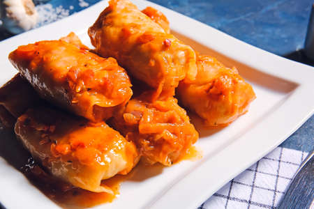 Plate with tasty stuffed cabbage rolls on color background